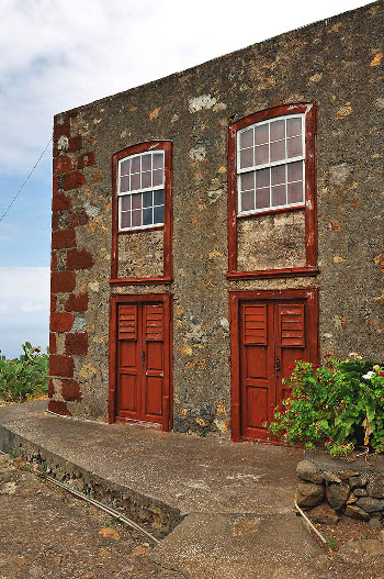 Casa de alto y bajo con gran regularidad en la distribución de sus vanos en la fachada. Sobresale el uso del sillar de tosca roja en las esquinas. Ventanas con dintel curvo, molduras de madera y tipo guillotina. El Tablado, Garafía, La Palma (foto: Sergio Socorro).